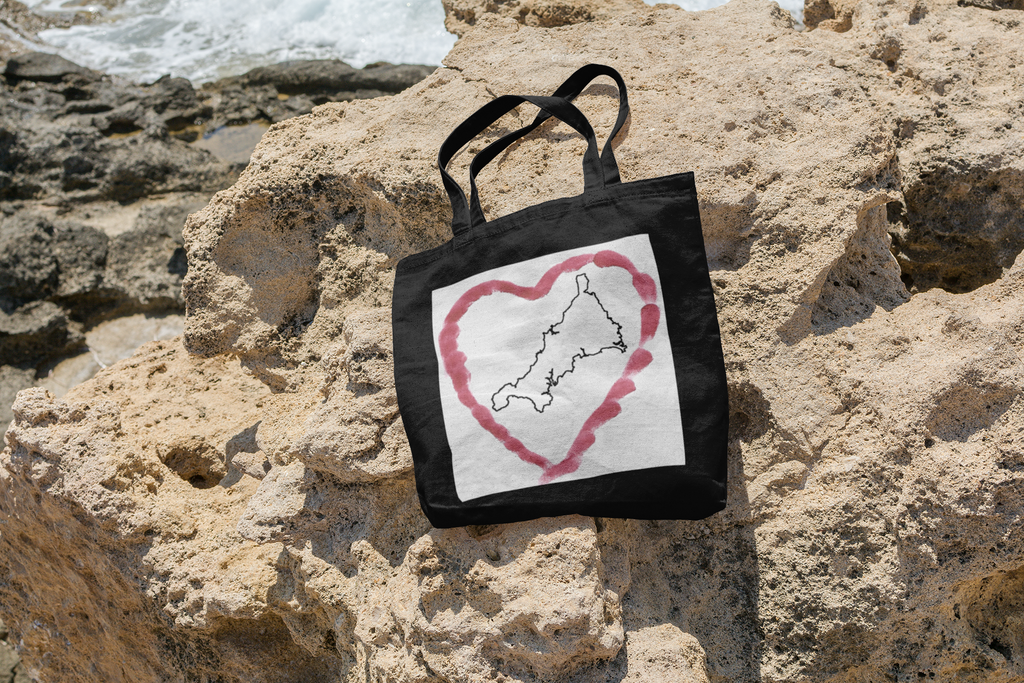 Black Cornwall tote bag with red Kernow heart map — bold Cornish gift bag on the rocks