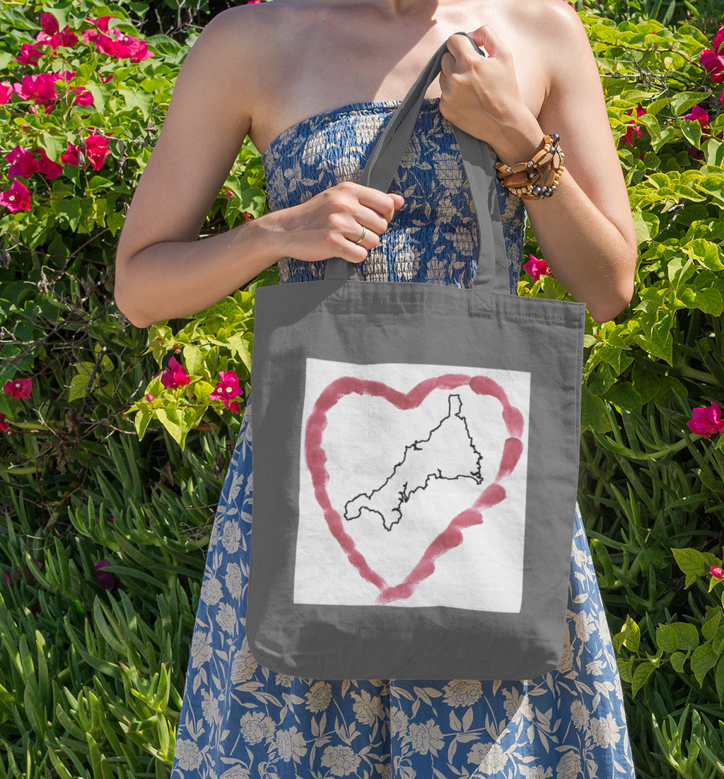 Grey I Love Cornwall tote bag with Kernow heart design — Cornish gift shopper in front of flowers.