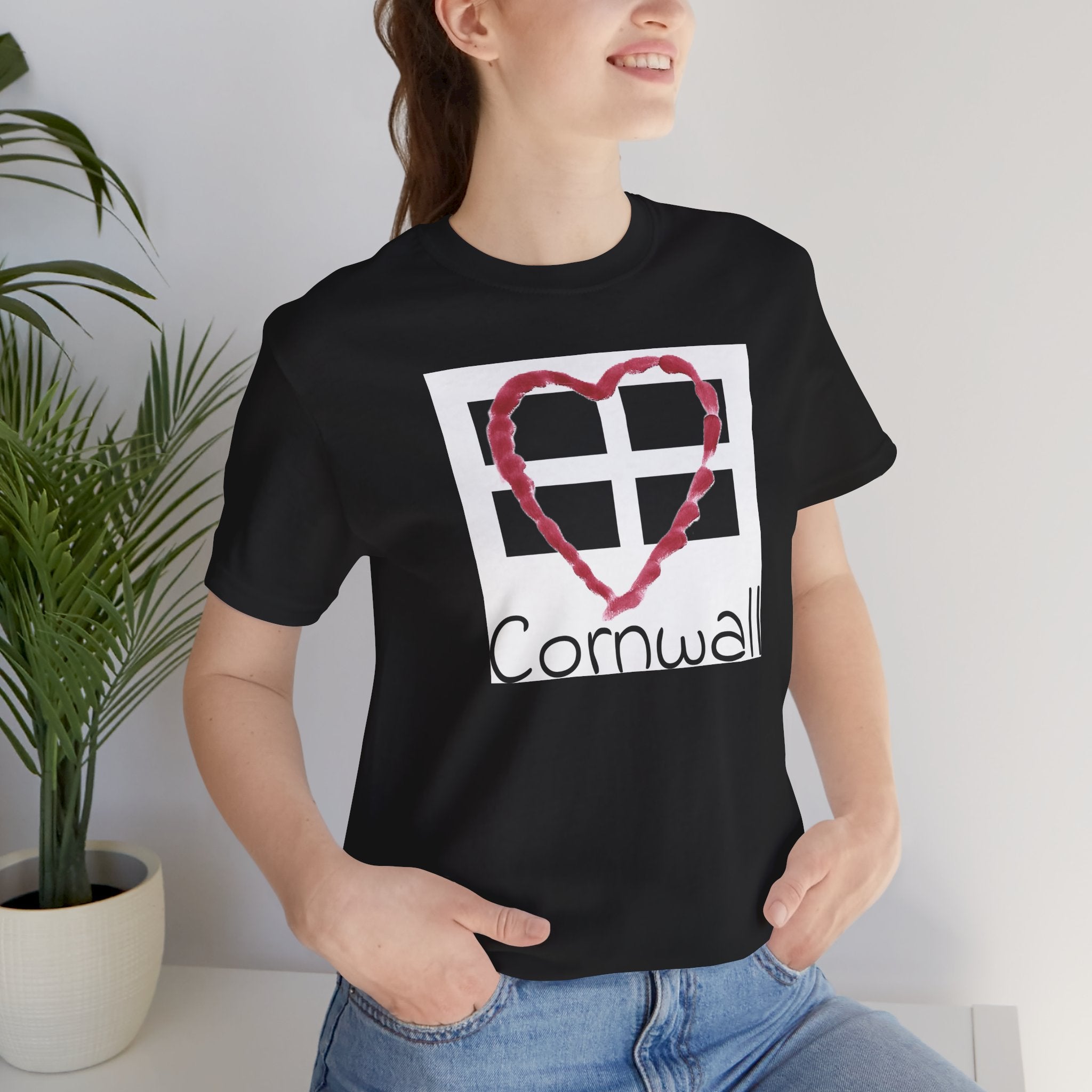 Holiday home woman sitting wearing black Cornwall Heart Flag graphic tee, casual outfit