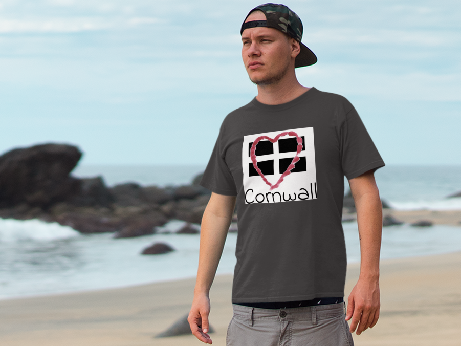 Man wearing Asphalt Cornwall Heart Flag t-shirt on rocky Cornwall beach