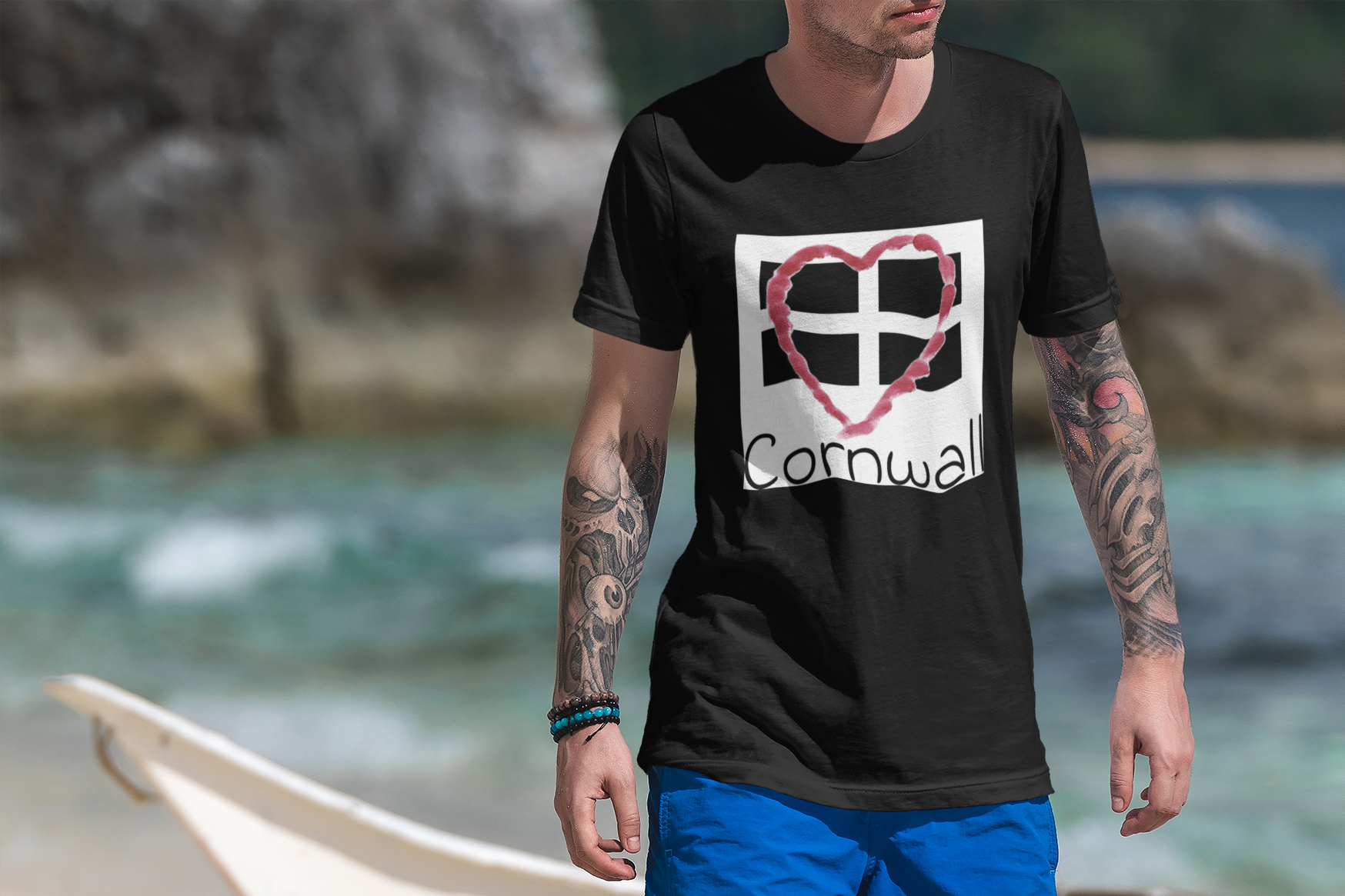 Man wearing black Cornwall Heart Flag t-shirt on rocky Cornwall beach