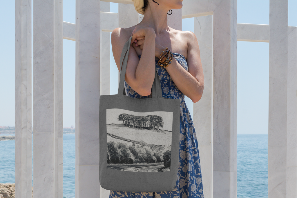 Woman carrying grey Nearly There Trees Cornwall tote bag on coastal walkway
