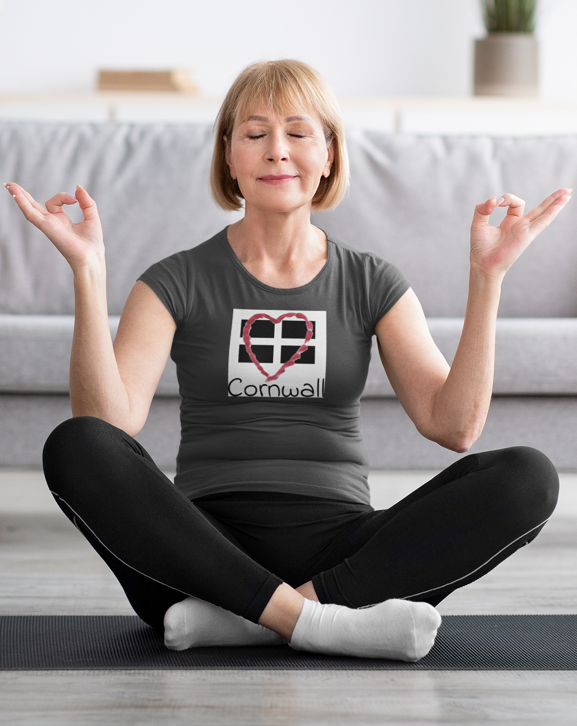Woman sitting wearing grey Cornwall Heart Flag graphic tee, casual outfi