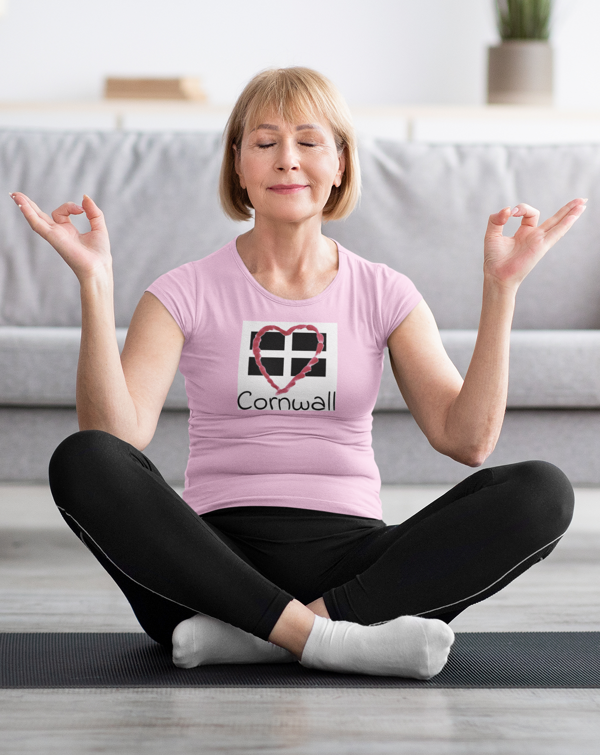 Woman sitting wearing pink Cornwall Heart Flag graphic tee, casual outfit