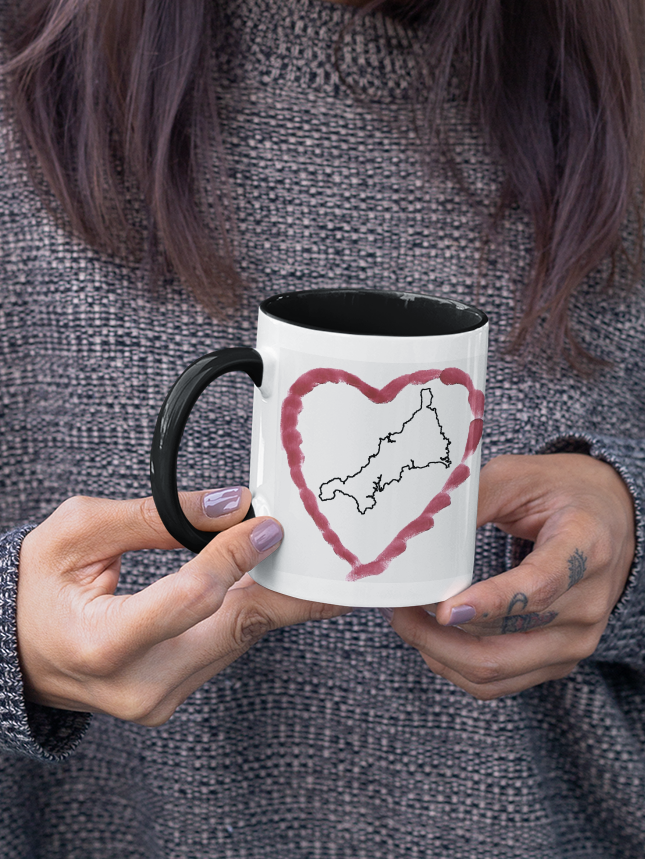 Hands holding I Love Cornwall heart map mug with black handle, Cornwall outline design