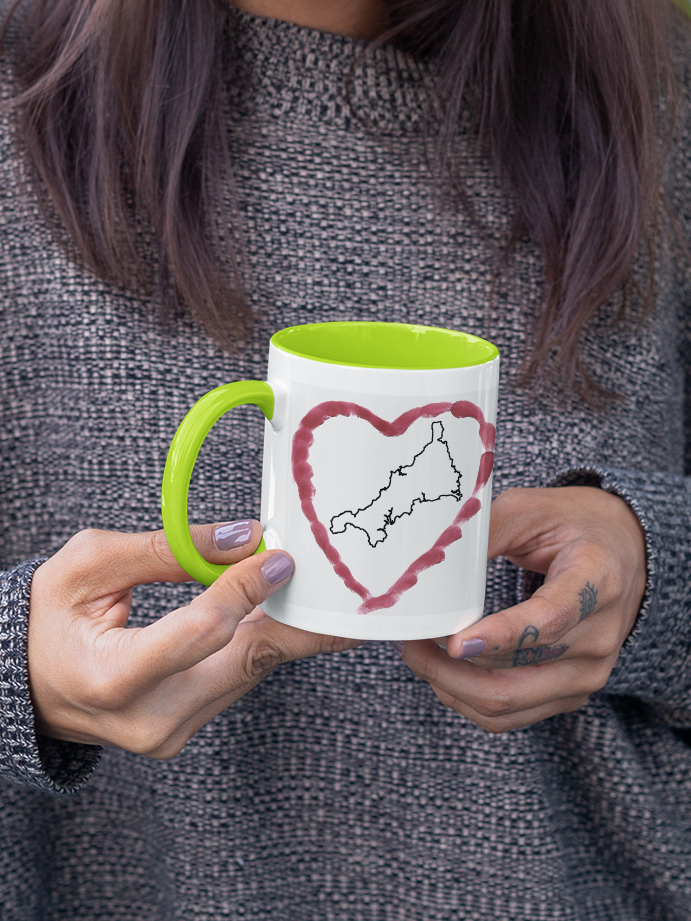 Hands holding I Love Cornwall heart map mug with green handle, Cornwall outline design