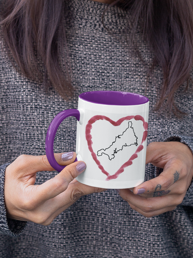 Hands holding I Love Cornwall heart map mug with purple handle, Cornwall outline design