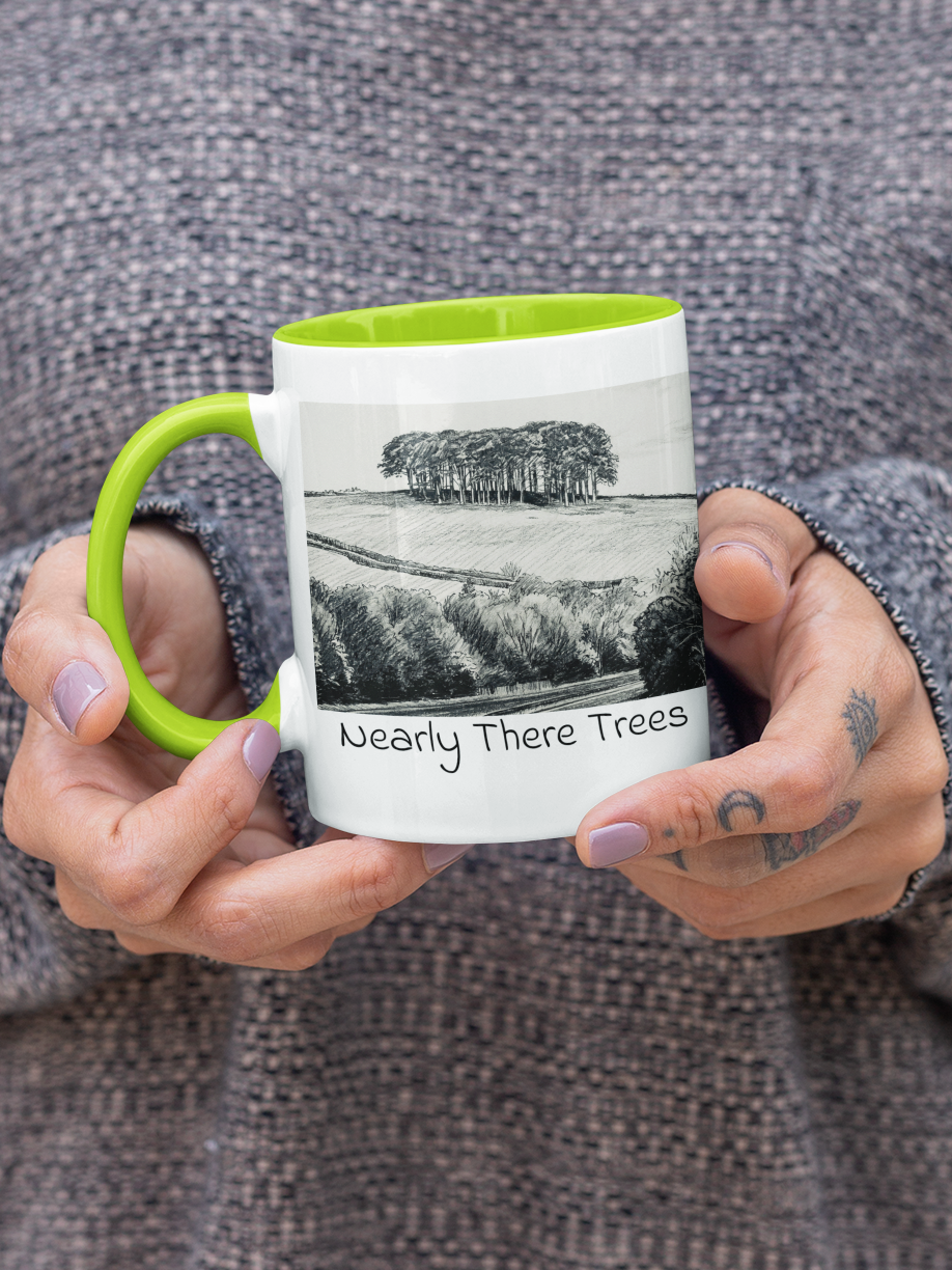 Hands holding Nearly There Trees mug with green handle, A30 Cornwall tree landscape pencil sketch design