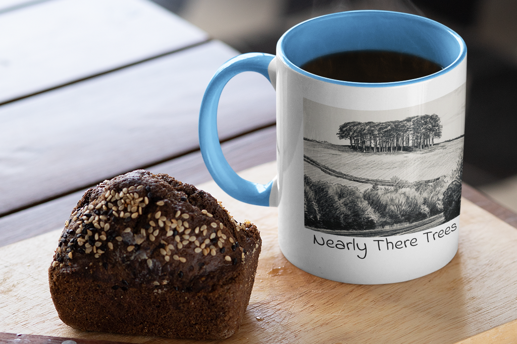 Nearly There Trees mug with light blue handle and steaming coffee beside muffin, Cornwall tree sketch design