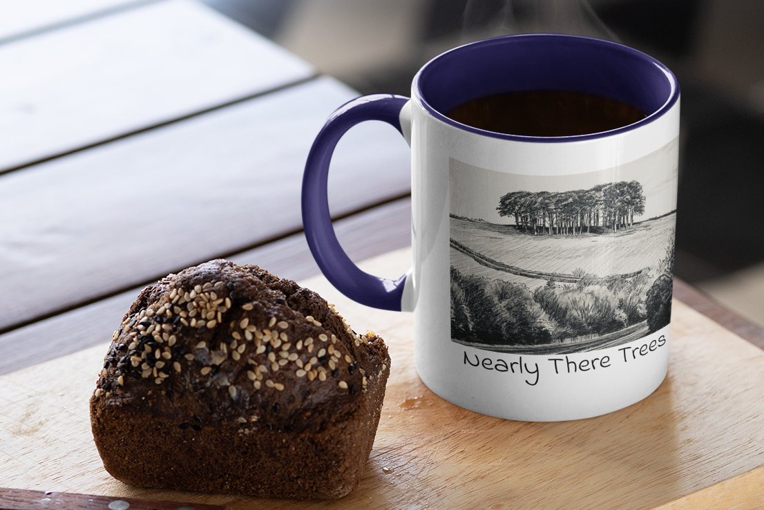 Nearly There Trees mug with navy handle and steaming coffee beside muffin, Cornwall tree sketch design