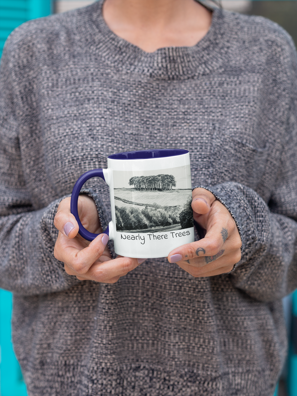 Woman holding Nearly There Trees mug with navy handle and interior, Cornwall tree sketch design