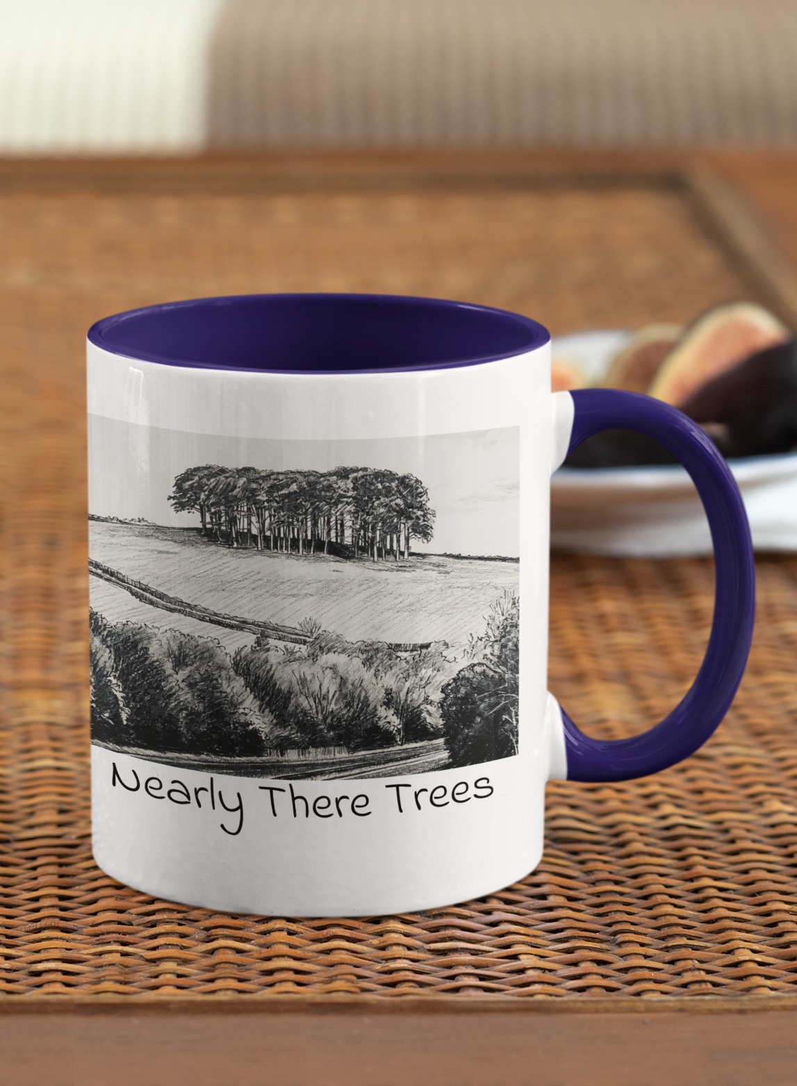Nearly There Trees mug with navy handle on wicker table, Cornwall tree landscape pencil sketch design