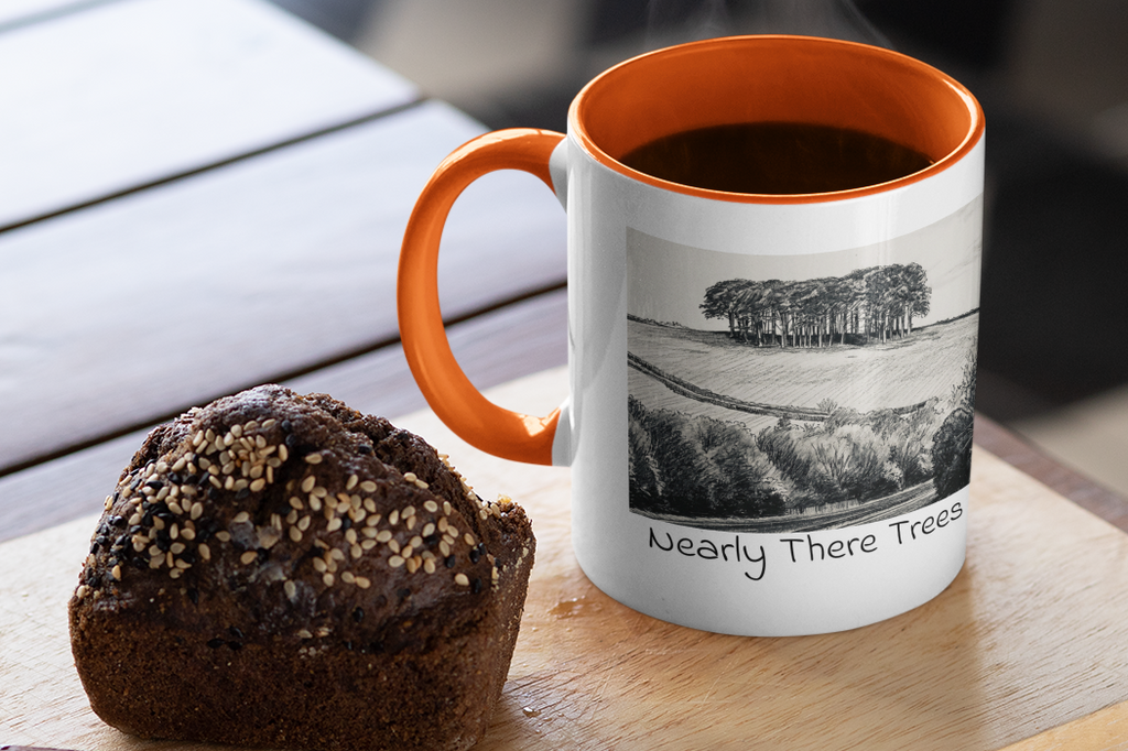 Nearly There Trees mug with orange handle and steaming coffee beside muffin, Cornwall tree sketch design