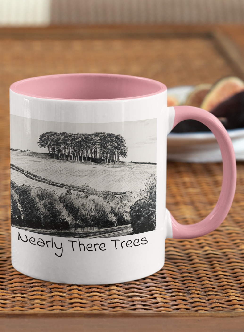 Nearly There Trees mug with pink handle on wicker table, Cornwall tree landscape pencil sketch design