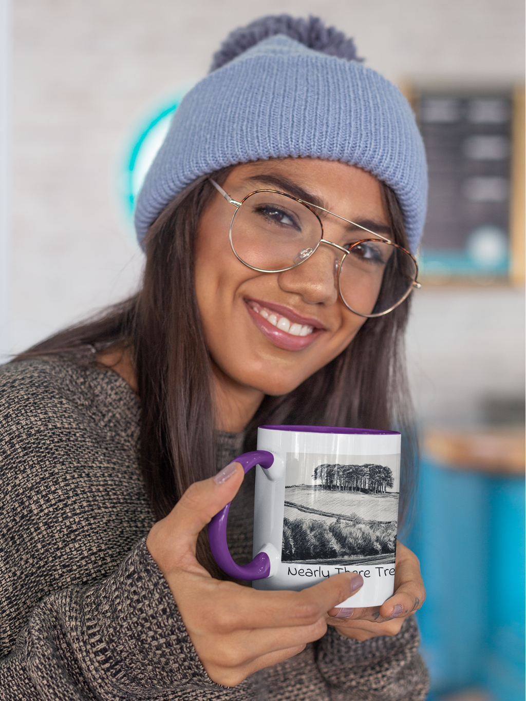 Woman in beanie holding Nearly There Trees mug with purple handle, tree line pencil sketch design