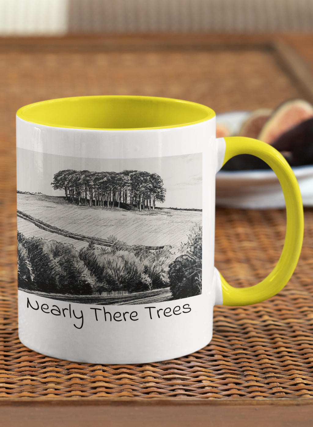 Nearly There Trees mug with yellow handle on wicker table, Cornwall tree landscape pencil sketch design