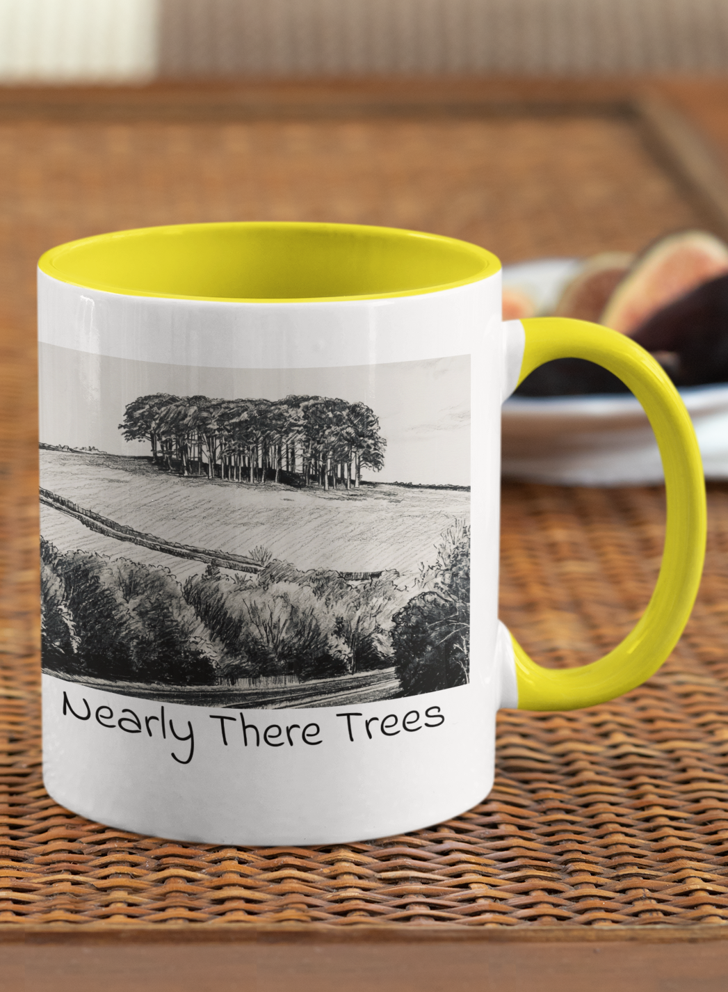 Nearly There Trees mug with yellow handle on wicker table, Cornwall tree landscape pencil sketch design