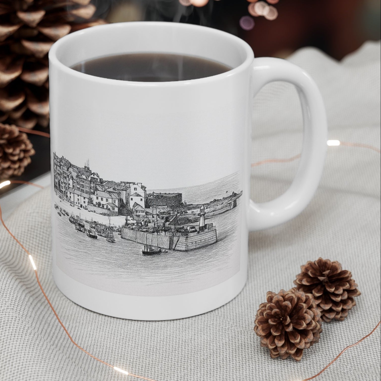 St Ives Harbour Cornwall mug with steaming coffee, styled with pinecones and fairy lights for festive gift photo
